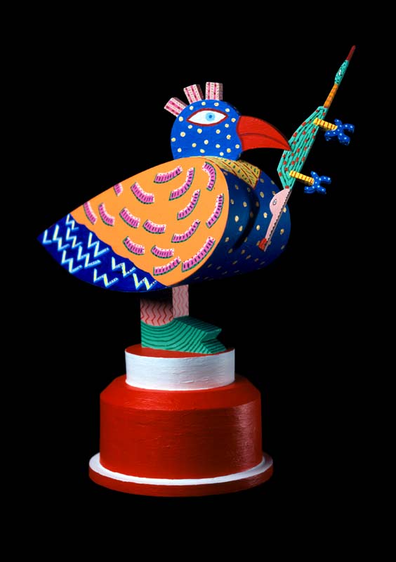 Ceram, een gekleurde vogel met een hagedis in zijn bek staande op een ronde machineonderdeel, &copy; Andr&eacute; Boone