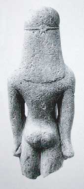 Kouros, achterzijdezijde, een kleine stenen naakte jongen. Het is een votiefgeschenk uit de oriëntaliserende periode +/- 600 voor Chr., van de Grieken. Omdat het beeldje in Amsterdam te bezichtigen is heeft het de naam ‘de Amsterdamse Kouros’ gekregen.