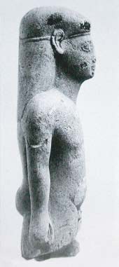 Kouros, rechterzijde, een kleine stenen naakte jongen. Het is een votiefgeschenk uit de oriëntaliserende periode +/- 600 voor Chr., van de Grieken. Omdat het beeldje in Amsterdam te bezichtigen is heeft het de naam ‘de Amsterdamse Kouros’ gekregen.