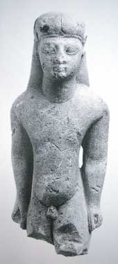 Kouros, voorzijde, een kleine stenen naakte jongen. Het is een votiefgeschenk uit de oriëntaliserende periode +/- 600 voor Chr., van de Grieken. Omdat het beeldje in Amsterdam te bezichtigen is heeft het de naam ‘de Amsterdamse Kouros’ gekregen.