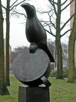 bronzen beeld, titel Nomen  Nescio is een opeenstapeling van drie elementen: de zuil of sokkel, een omgevallen kopje en soort kraai-achtige vogel, © André Boone