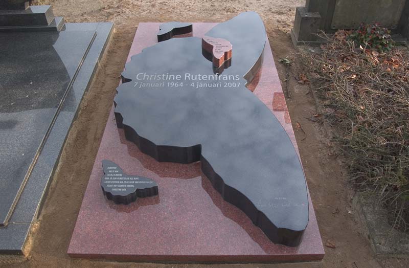 Het graf van Christine Rutenfrans. Een grote zwarte granieten vlinder ligt op een rood granieten plaat van een bij twee meter. De inscriptie luidt Christine Rutenfrans 7 januari 1964 - 4 januari 2007 een kus van Lex Stijn Emiel Ellemijn